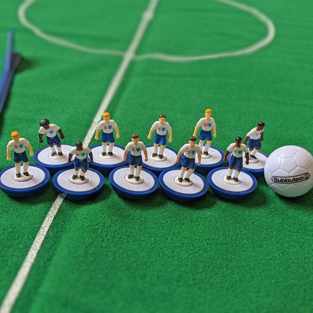 Subbuteo England Edition Main Game with player figures and ball on a green tabletop football field.